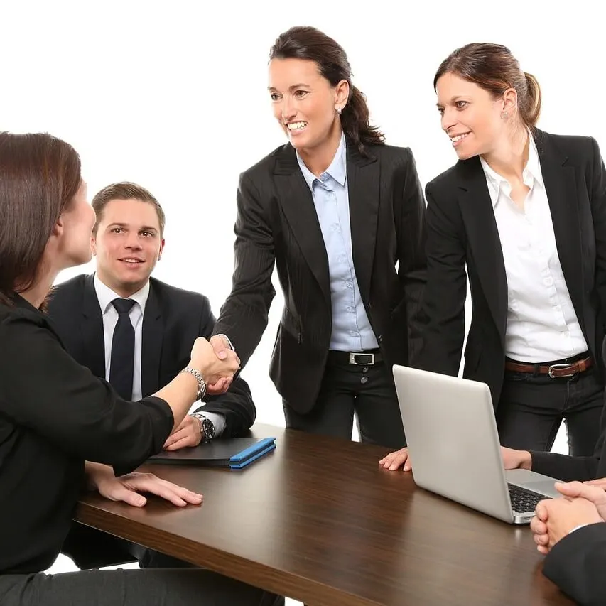 Business people in suits shaking hands across a conference table